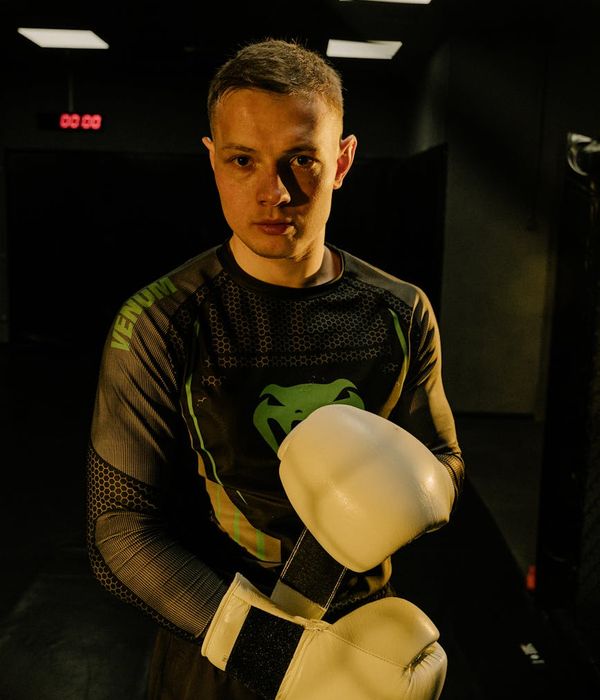 Man performing a strength exercise in a dark gym with lilac light.